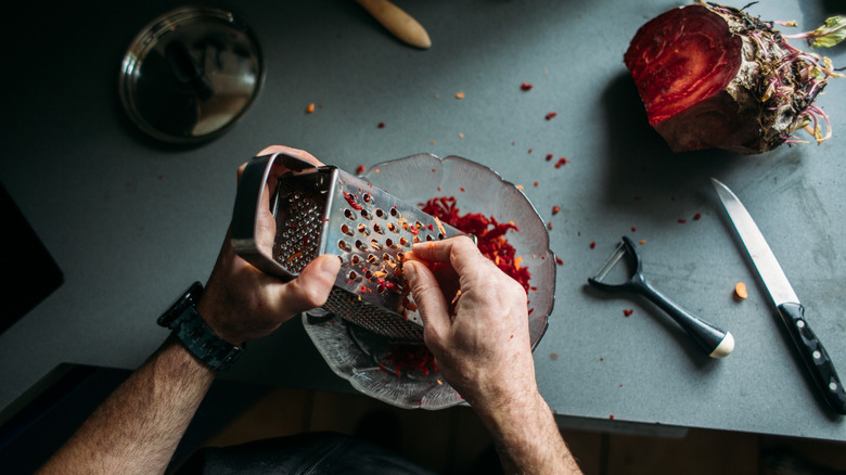 Hands grating vegetables